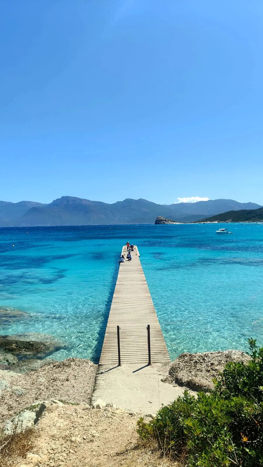 Pont en bois sur la plage sauvage du Lotu en Corse, accès vers une mer turquoise dans le désert des Agriates.