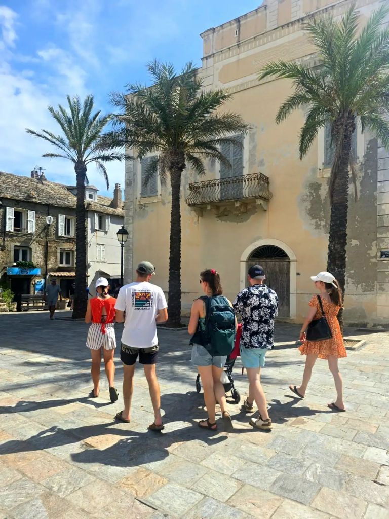 Groupe de personnes marchant dans les ruelles pavées du village pittoresque d’Erbalunga en Corse